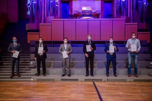 Absolvierende auf der Treppe vor der Orgel im Audimax mit Urkunde und Maske (Foto:RUB/Marquard)