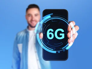 Männerhand zeigt Telefonbildschirm mit leuchtendem 6G-Symbol, großformatiger Kopierraumhintergrund. Display mit digitalem Hologramm der Internetverbindung und futuristischer Technologie.