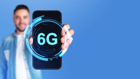 Männerhand zeigt Telefonbildschirm mit leuchtendem 6G-Symbol, großformatiger Kopierraumhintergrund. Display mit digitalem Hologramm der Internetverbindung und futuristischer Technologie.