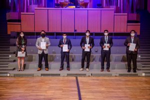 Absolvierende auf der Treppe vor der Orgel im Audimax mit Urkunde und Maske (Foto:RUB/Marquard)