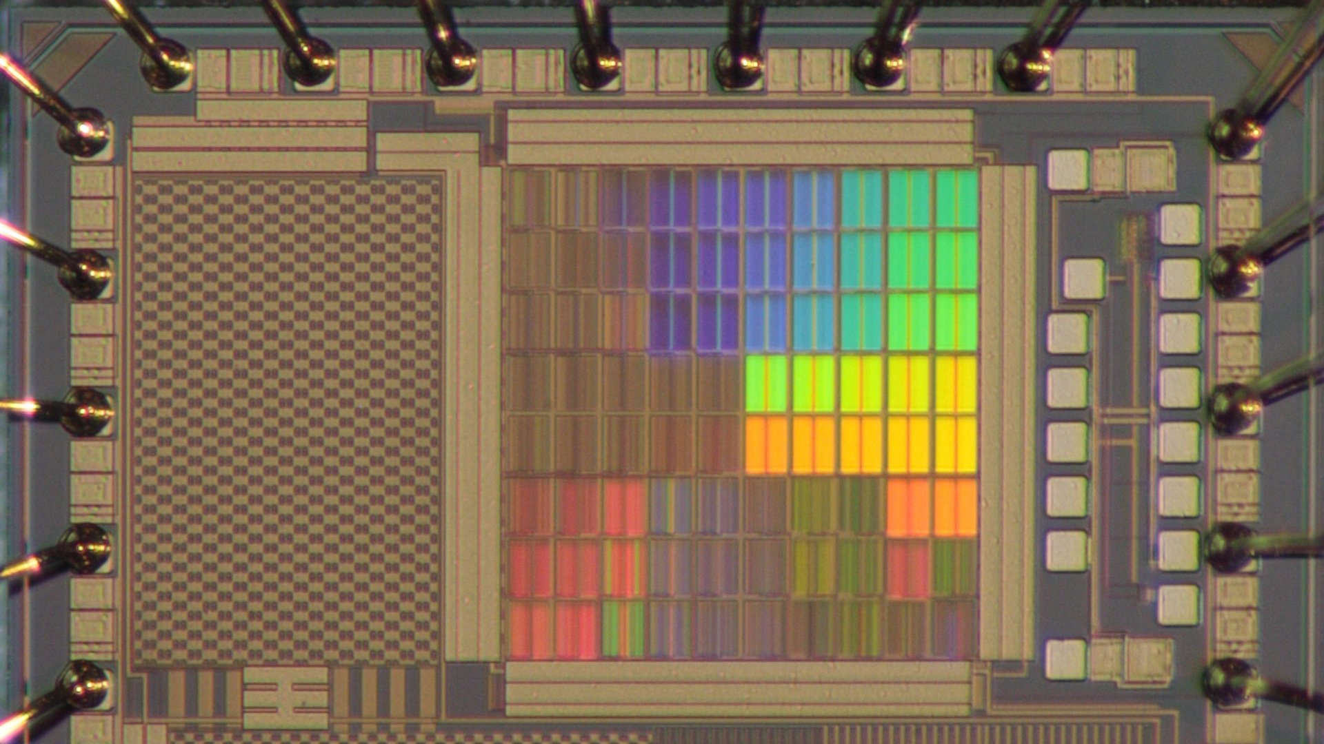 Zu sehen ist ein Testchips mit optisch wirksamen integrierten Strukturen, die regenbogenfarben schimmern. (© Fakultät ETIT/Archiv/Lehrstuhl AIS)