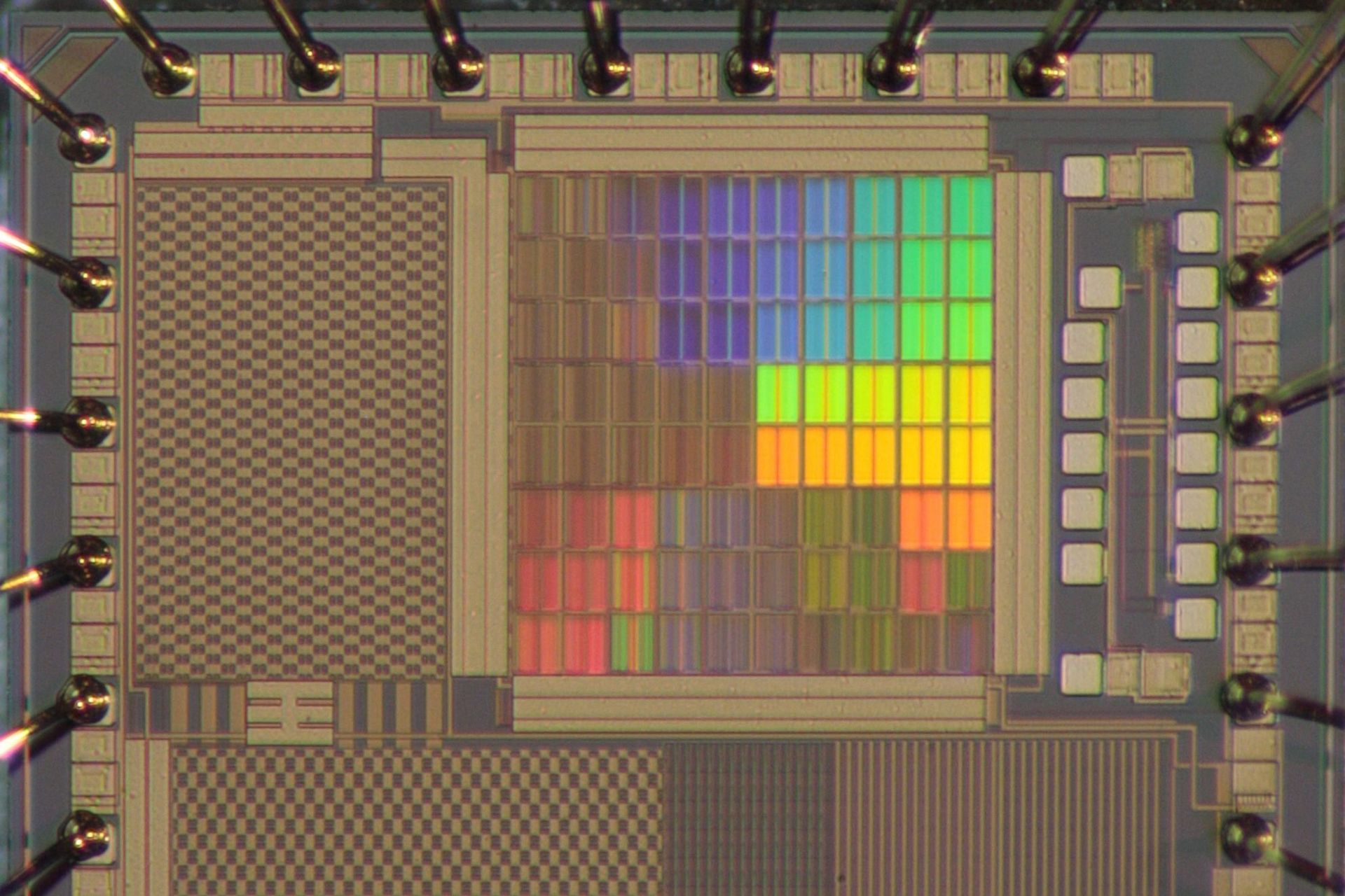 Zu sehen ist ein Testchips mit optisch wirksamen integrierten Strukturen, die regenbogenfarben schimmern. (© Fakultät ETIT/Archiv/Lehrstuhl AIS)