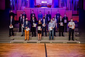 Absolvierende auf der Treppe vor der Orgel im Audimax mit Urkunde und Maske(Foto:RUB/Marquard)