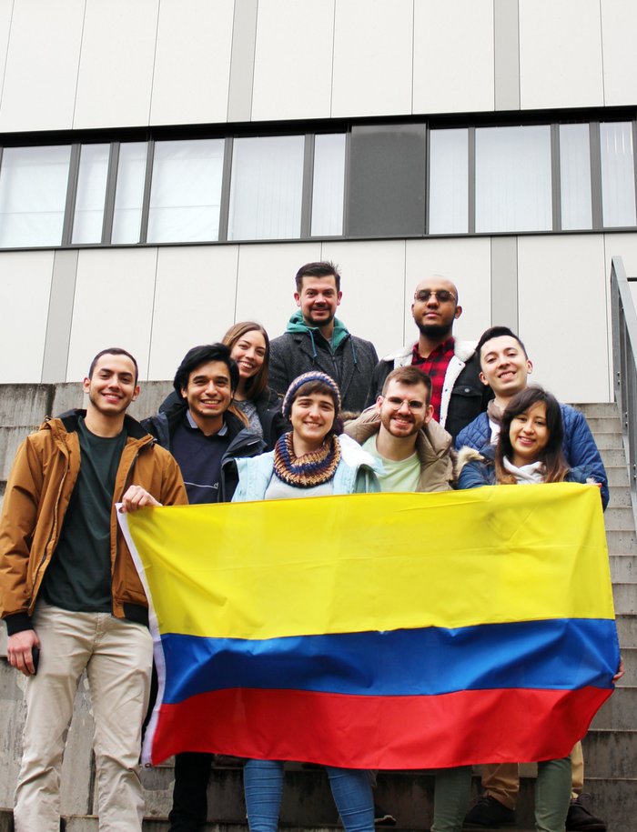 Unsere acht Double Degree Studierenden mit kolumbianischer Flagge in der Hand und Double Degree Koordinator Dr. Christoph Baer. (© RUB/Zeitel)