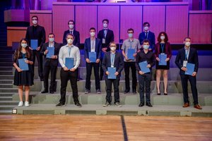 Absolvierende auf der Treppe vor der Orgel im Audimax mit Urkunde und Maske (Foto:RUB/Marquard)