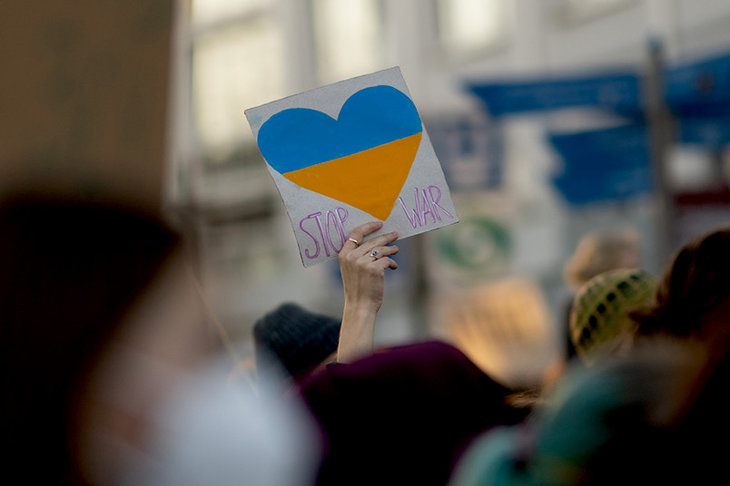 Ein Demonstrationsschild wird in die Luft gehalten auf dem steht: "Stop War". Darauf ein Herz in den Farben der Ukraine.(© RUB, Kramer)